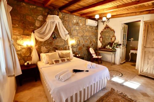 a bedroom with a bed in a stone wall at Kemerbag 29 Guest House 12 Yaş Üstü in Bozcaada