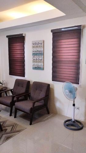 a waiting room with two chairs and a fan at Casa LeoMa in Cavite