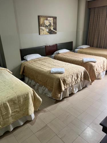 a room with three beds with towels on them at Hotel Rizzo in Guayaquil
