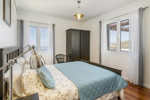 ein Schlafzimmer mit einem Bett und zwei Fenstern in der Unterkunft Villa Casa Das Orquideas by Villa Plus in Estreito da Calheta