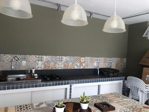 a kitchen with a table and three lights at Solar dos Cataventos: Linda Casa com Piscina e Jacuzi in Florianópolis