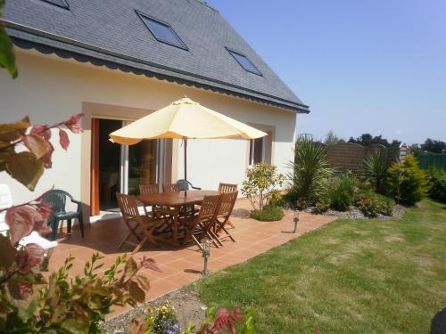a patio with a table and an umbrella at Gite bord de mer jacuzzi in Plougrescant