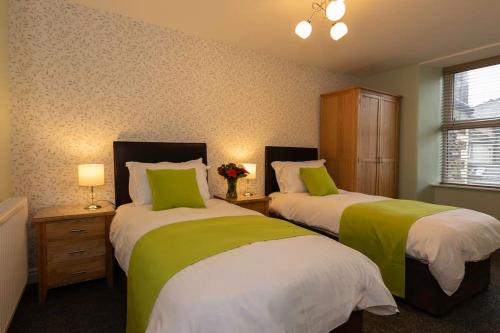 1 dormitorio con 2 camas con sábanas verdes y blancas en Biskey Bowness, en Bowness-on-Windermere