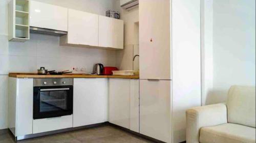 a kitchen with white cabinets and a stove and a couch at Nicely furnished 1 bedroom apartment in Gzira in Il-Gżira