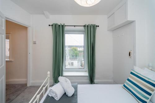 1 dormitorio con una gran ventana con cortinas verdes en Bright and Modern 4 bed house- TV IN EVERY ROOM, en Port Talbot