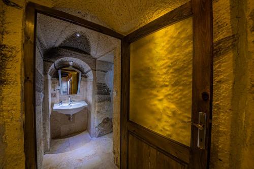 a bathroom with a sink and a wooden door at Konak Bezirhane Cave Otel in Urgup