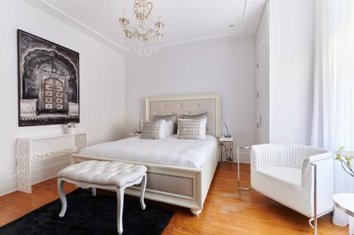 a white bedroom with a bed and a chandelier at Villa Dante By Denstays in Montréal