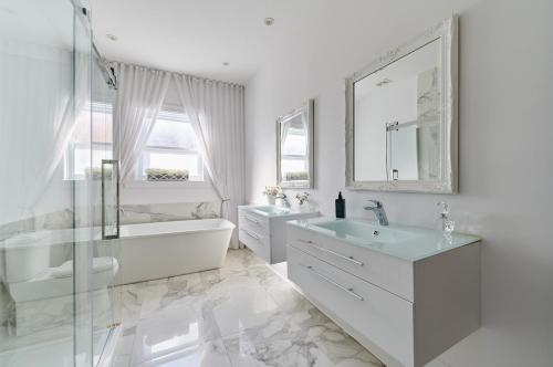 a white bathroom with a tub and a sink at Villa Dante By Denstays in Montréal