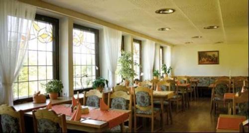 un comedor con mesas, sillas y ventanas en Hotel Zum Alten Brauhaus, en Kurort Oberwiesenthal