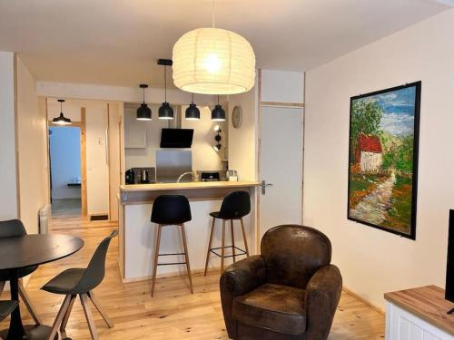 uma sala de estar com uma cadeira, uma mesa e uma cozinha em Appartement à Valognes : Entre Terre et Mer em Valognes
