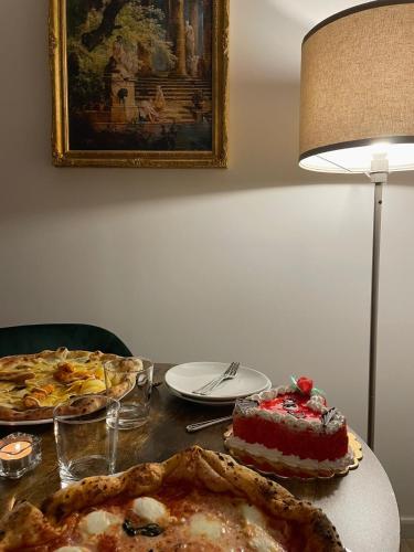 a table with a pie and a pizza and a lamp at GUALTIERI LUXURY SUITE in San Giorgio a Cremano