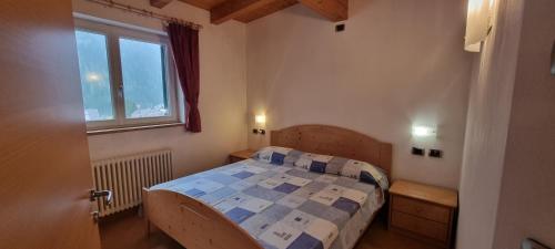 ein kleines Schlafzimmer mit einem Bett und einem Fenster in der Unterkunft Casa Soraruf in Campitello di Fassa