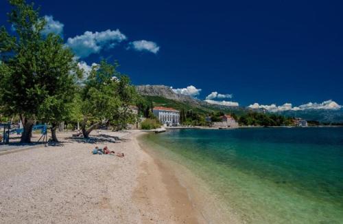 uma praia com pessoas deitadas na areia e na água em Jolie Ann Marie apartment em Kaštela