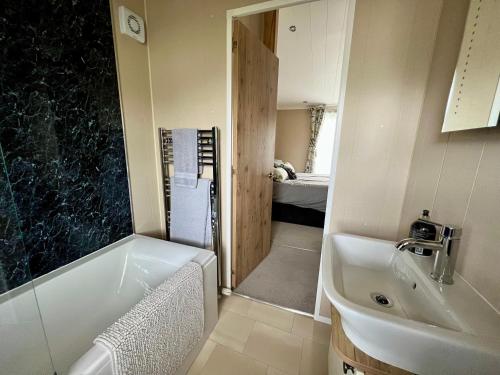 een kleine badkamer met een bad en een wastafel bij Wyndham Lodge in South Cerney