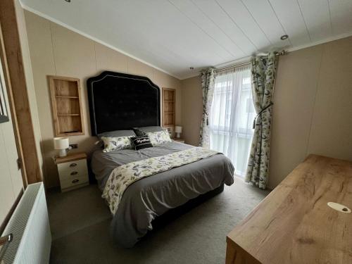 een slaapkamer met een bed en een groot raam bij Wyndham Lodge in South Cerney