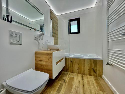 a bathroom with a toilet and a sink and a tub at Residence Odaile #1 in Otopeni