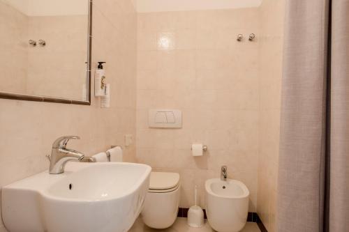 a white bathroom with a sink and a toilet at Villa Arizona in Milano Marittima