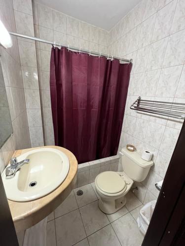 a bathroom with a toilet sink and a purple shower curtain at Hotel Rizzo in Guayaquil