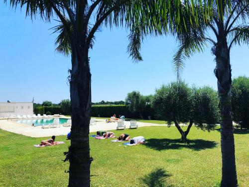 a group of people laying in the grass near a swimming pool at Torre Santo Stefano in Otranto