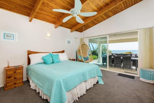 a bedroom with a bed and a ceiling fan at Pats Place on the Beach in Papamoa