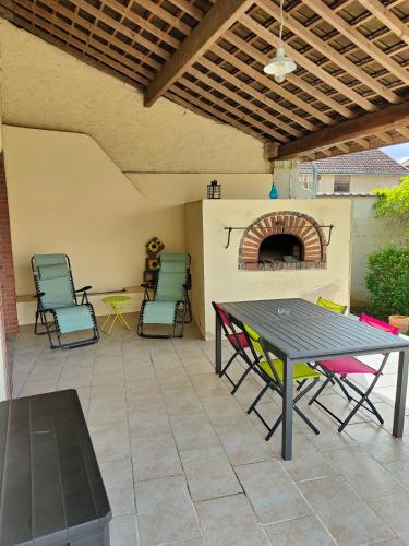 un patio avec une table, des chaises et une cheminée dans l'établissement Gîte Saint Mard, à Saint-Mard-lès-Rouffy