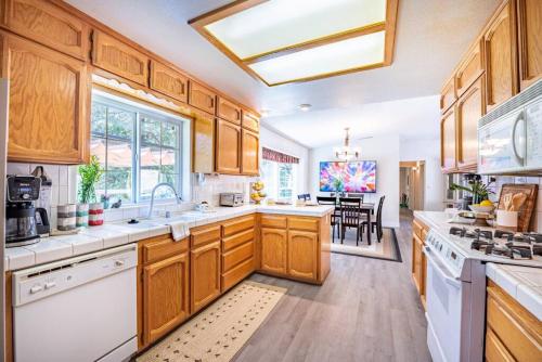 a large kitchen with wooden cabinets and white appliances at Manic Mountain Forest Cabin 3 miles from Bass Lake in Oakhurst