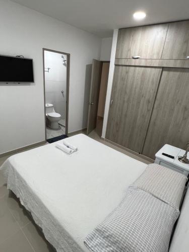 a bedroom with a large white bed and a bathroom at Lujoso apartamento central in Montería