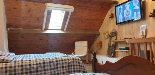 a bedroom with two beds and a tv on the wall at Le chalet des nounours in Boutx