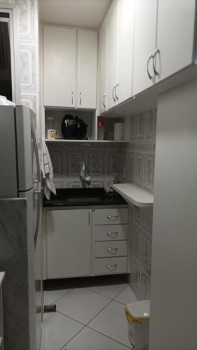 a kitchen with white cabinets and a sink and a refrigerator at Ap no melhor lugar do Centro com elevador, wi-fi e Smart TV in Vitória