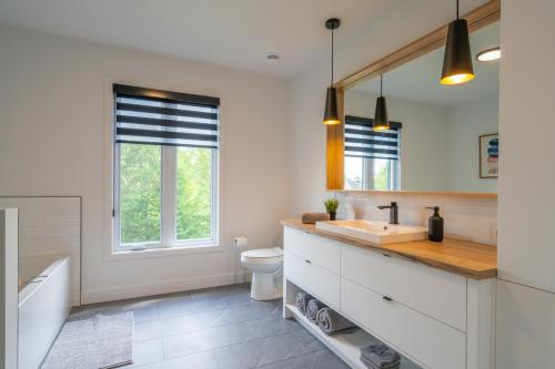 een badkamer met een wastafel, een toilet en een spiegel bij Halte 4 Saisons- en nature à 5 min du Mont-Orford! in Orford