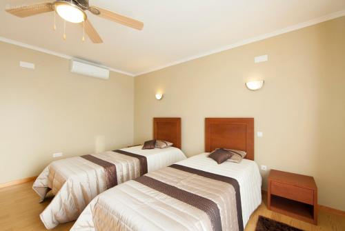 two beds in a room with a ceiling fan at Villa Da Madalena in Madalena
