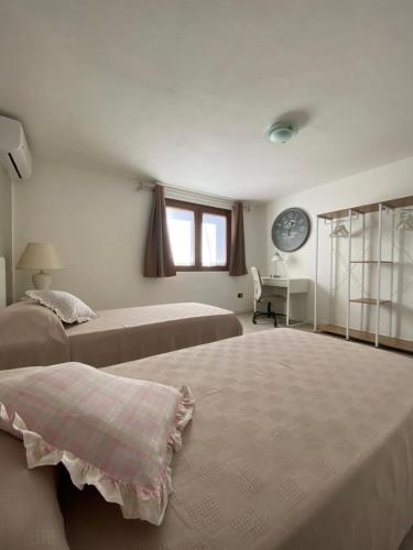 Spazio Friuli - Tiare Apt. residenza nel verde في Sevegliano: غرفة نوم بسريرين وساعة على الحائط