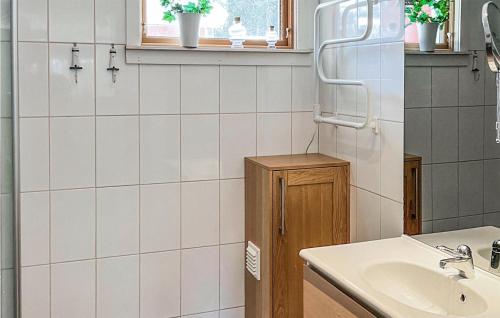 een wit betegelde badkamer met een wastafel en een spiegel bij 3 Bedroom Lovely Home In Frnsta in Fränsta