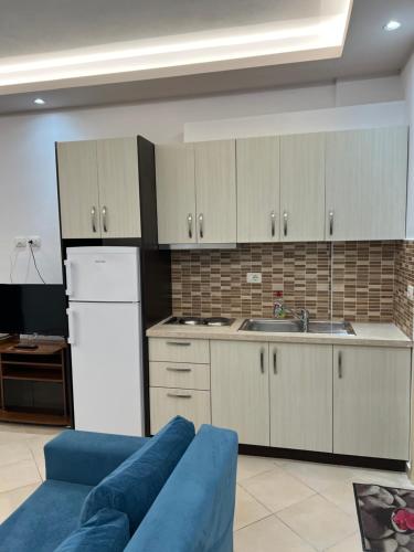 a kitchen with a blue couch and a white refrigerator at Hotel Arsenal in Ksamil