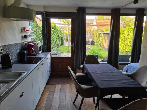 een keuken met een tafel en stoelen en een keuken met een raam bij Bed & Breakfast 28 appartement met ruime tuin en gratis prive parkeren ideaal voor gezinnen in Assen
