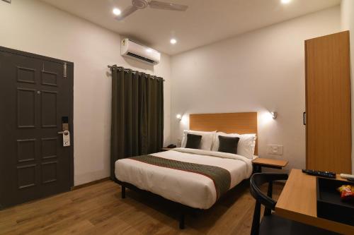 a hotel room with a large bed and a desk at Super Townhouse Royapettah Near U.S Consulate in Chennai