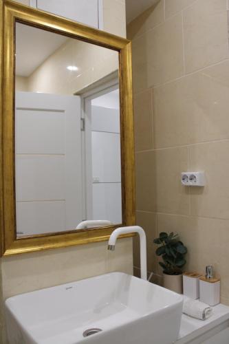 La salle de bains est pourvue d'un lavabo blanc et d'un miroir. dans l'établissement Apartament Maia, à Turda