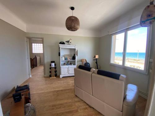 a living room with a couch and a view of the beach at Spa privatif face mer Riva Romantic & SPA in Ouistreham
