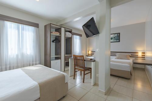 a hotel room with a bed and a desk and a tv at Bristol Portal do Iguaçu Curitiba Aeroporto in Curitiba