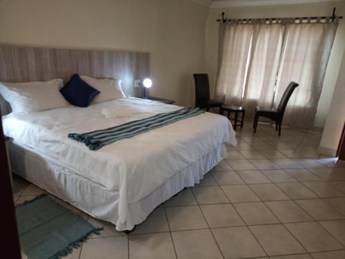 a bedroom with a large white bed and a table and chairs at 4 SEASONS COUNTRY CLUB in Bronkhorstspruit