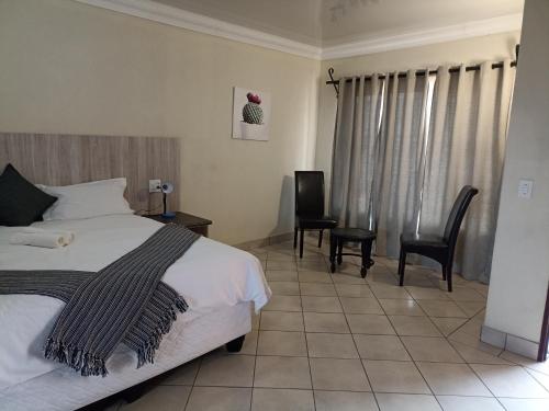 a bedroom with a bed and two chairs in it at 4 SEASONS COUNTRY CLUB in Bronkhorstspruit