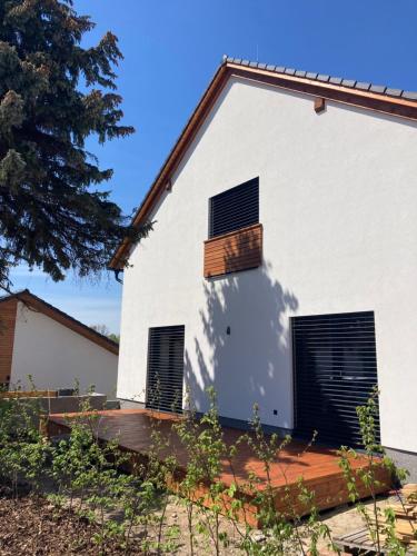 a white house with two windows and a wooden deck at Apartmány Na Lánech in Litomyšl