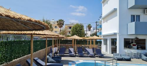 un complejo con sillas y sombrillas y una piscina en JP Pool & Apartments, en Kardamaina