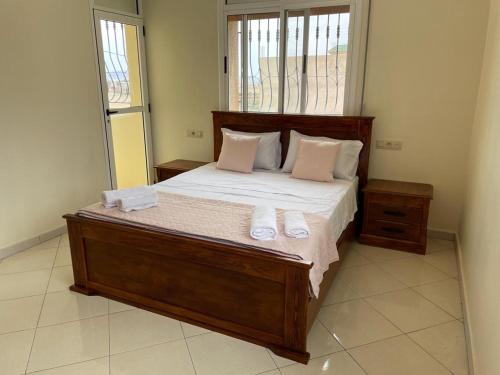 1 dormitorio con 1 cama grande de madera y toallas. en Villa Ihaddadene en Nador