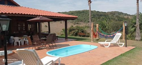 een patio met een zwembad en stoelen en een huis bij chale da montanha in Taubaté