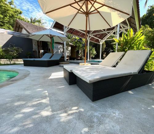 een patio met stoelen, een parasol en een zwembad bij Omala Village Gili Air in Gili Air