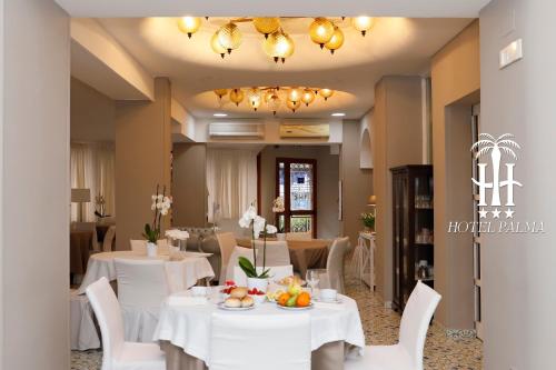 un comedor con mesas blancas y sillas blancas en Hotel Palma en Castellammare di Stabia