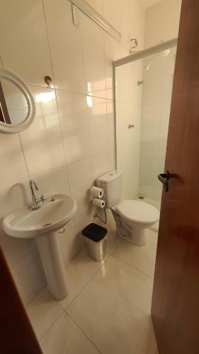 a white bathroom with a sink and a toilet at Pousada São José in Guaratinguetá