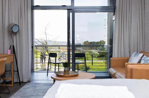a bedroom with a bed and a couch and a balcony at Menlyn Maine Trilogy Apartment 101 in Pretoria