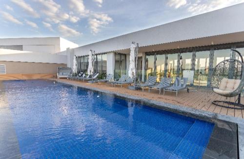 a large swimming pool with chairs and a building at Menlyn Maine Trilogy Apartment 101 in Pretoria